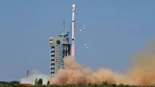 A white and red chinese long march 4c rocket launches into a blue sky