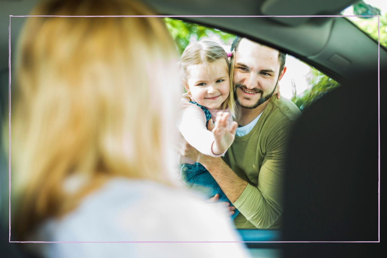 Smiling dad holding daughter waving goodbye to mum as she drives away