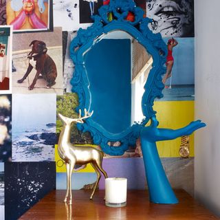 blue mirror with gold accessories and photos on wall