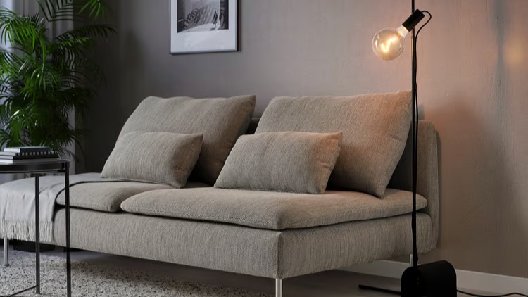 Black IKEA H&amp;Auml;RSLINGA floor lamp with adjustable head, styled in a living room beside a sofa