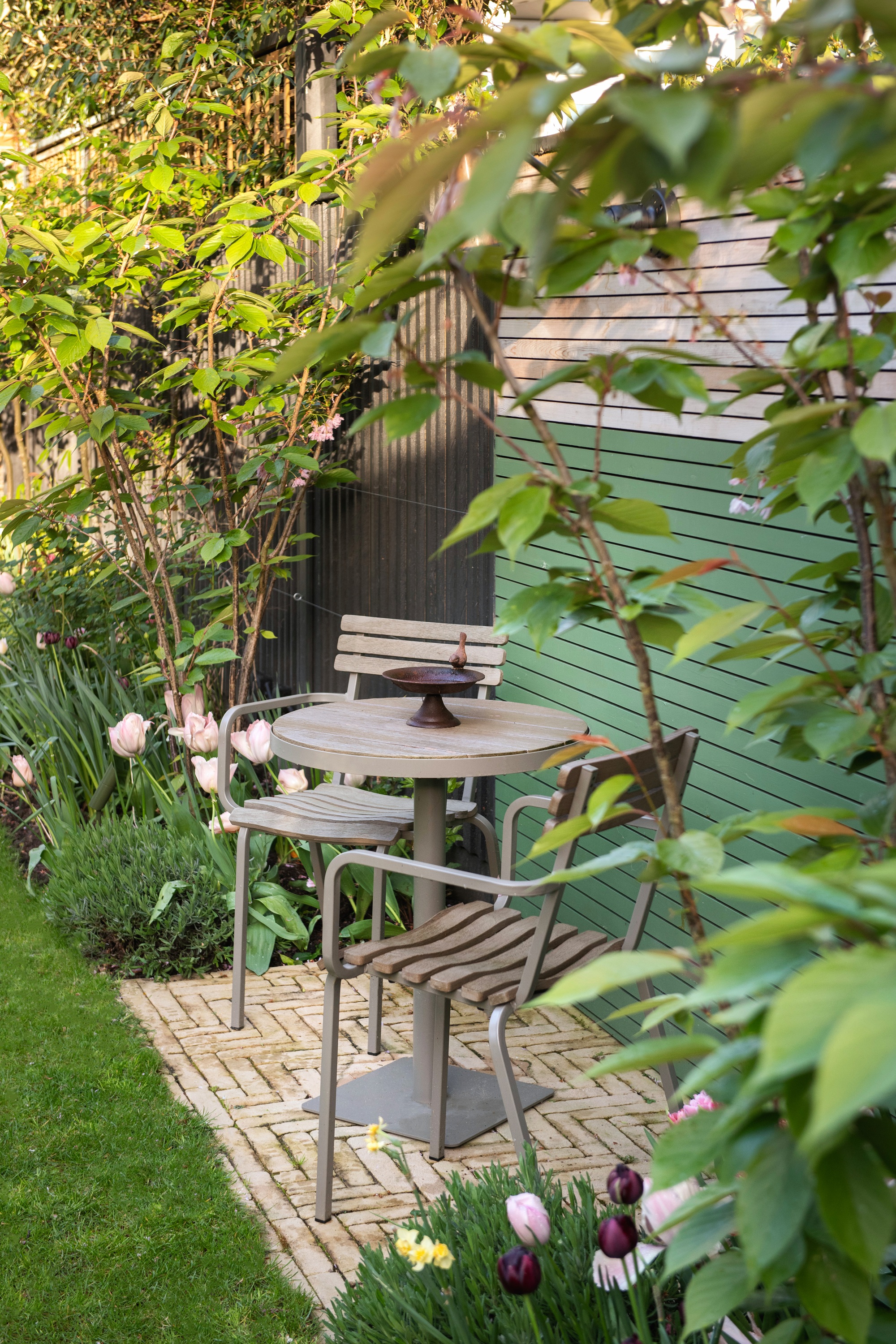 a small bistro table set in a garden on a small patio