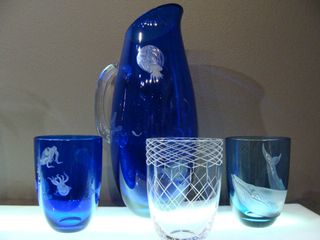 Two dark blue glasses and one clear glass alongside and blue water jug.