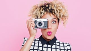 Girl holding digital camera to face with a surprised look