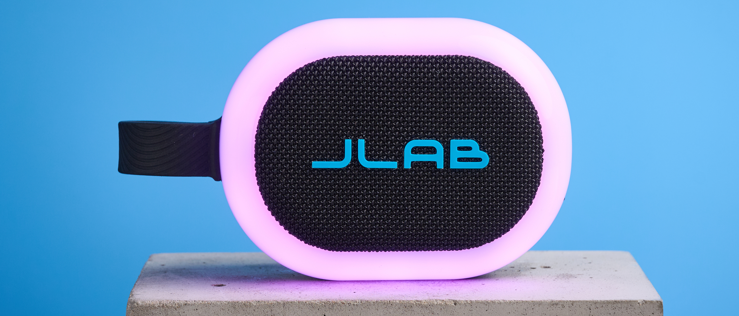 JLab Pop Party portable Bluetooth speaker with RGB lighting photographed on a blue background. 