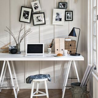 home office room with photoframes on white wall and white desk with stool