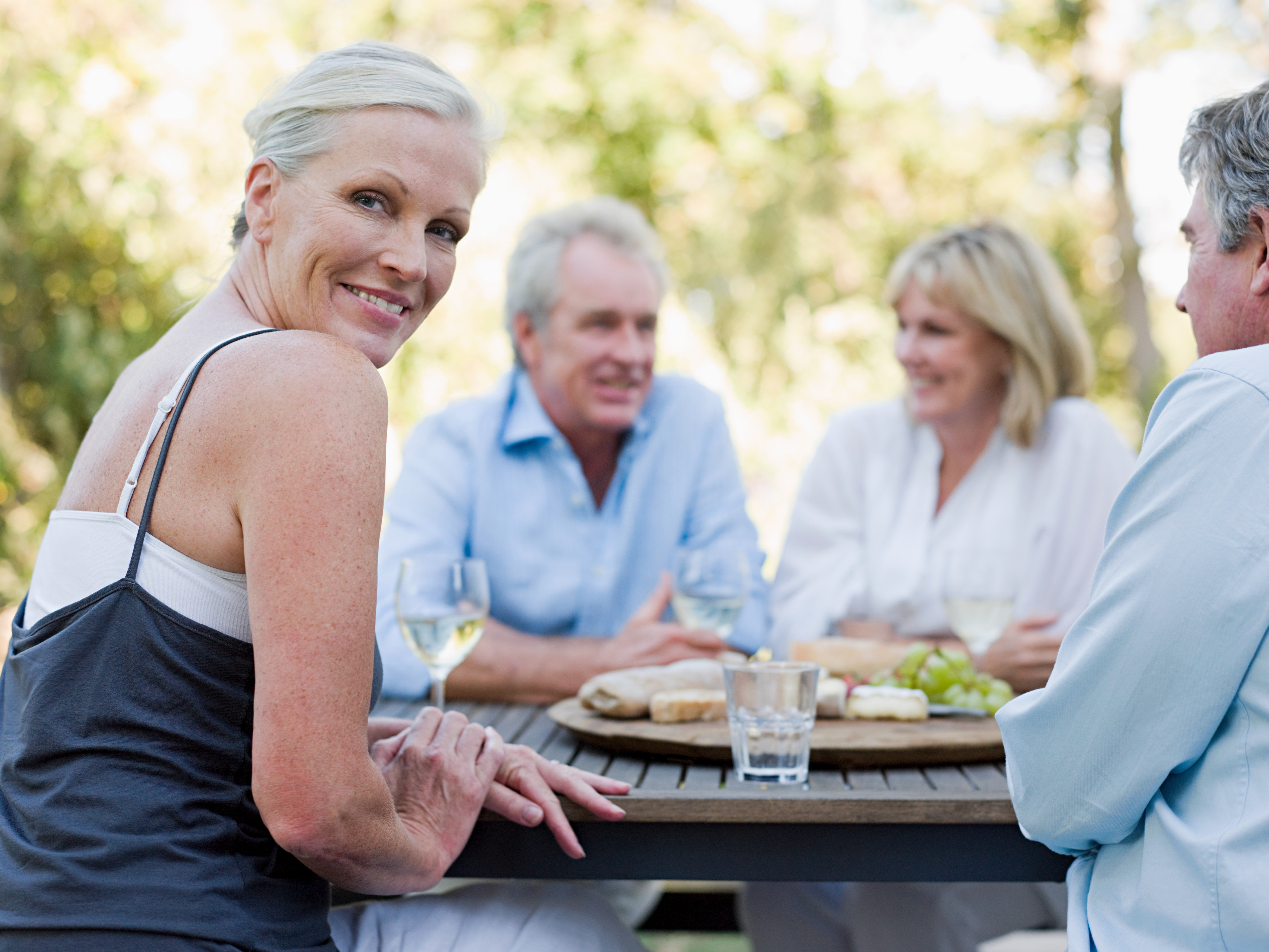 Two couples at an outdoor table. One woman looks directly at the camera.