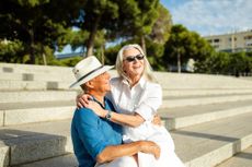 Happy senior couple embracing and laughing on outdoor steps, enjoying successful retirement and travel together