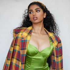 Actress Avantika wearing a multi-colored plaid blazer with a lime green bustier dress. 
