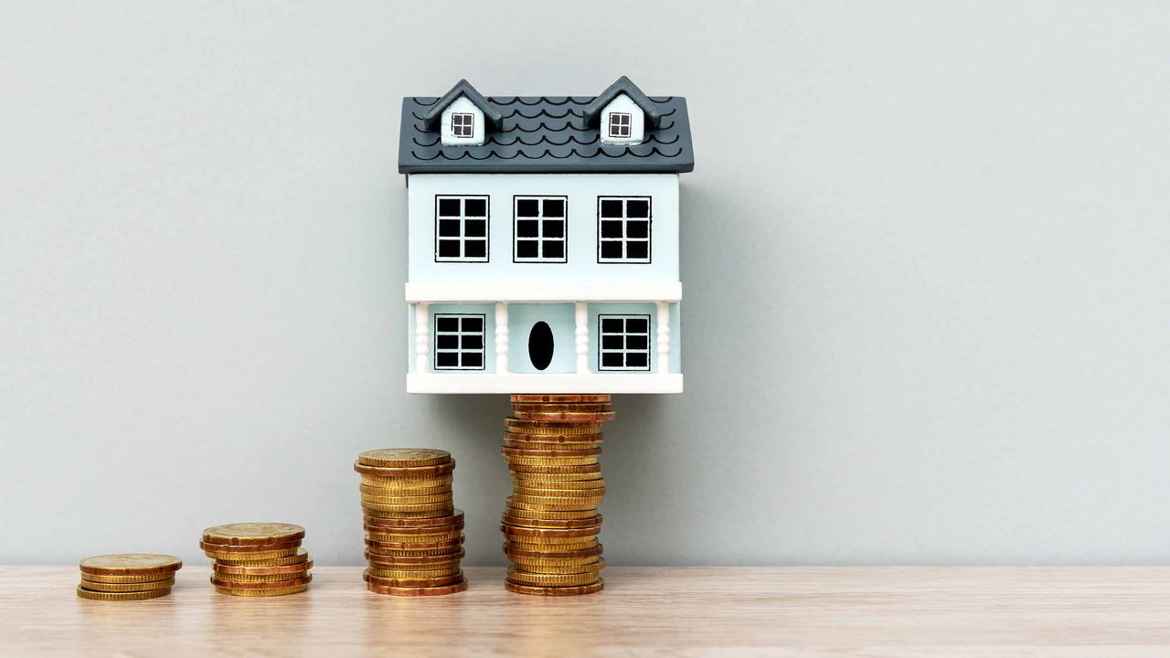 tiny wooden house on stacks of coins