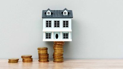 tiny wooden house on stacks of coins