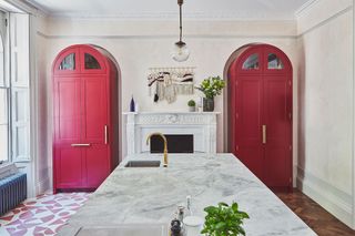 A large kitchen with bright red cabinets and a marble island countertop
