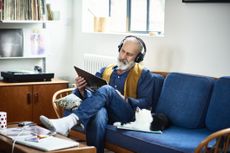 Man sits on sofa listening to headphones.