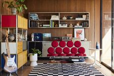a mid century style room with herman millers marshmallow sofa in red in. there's storage and guitar