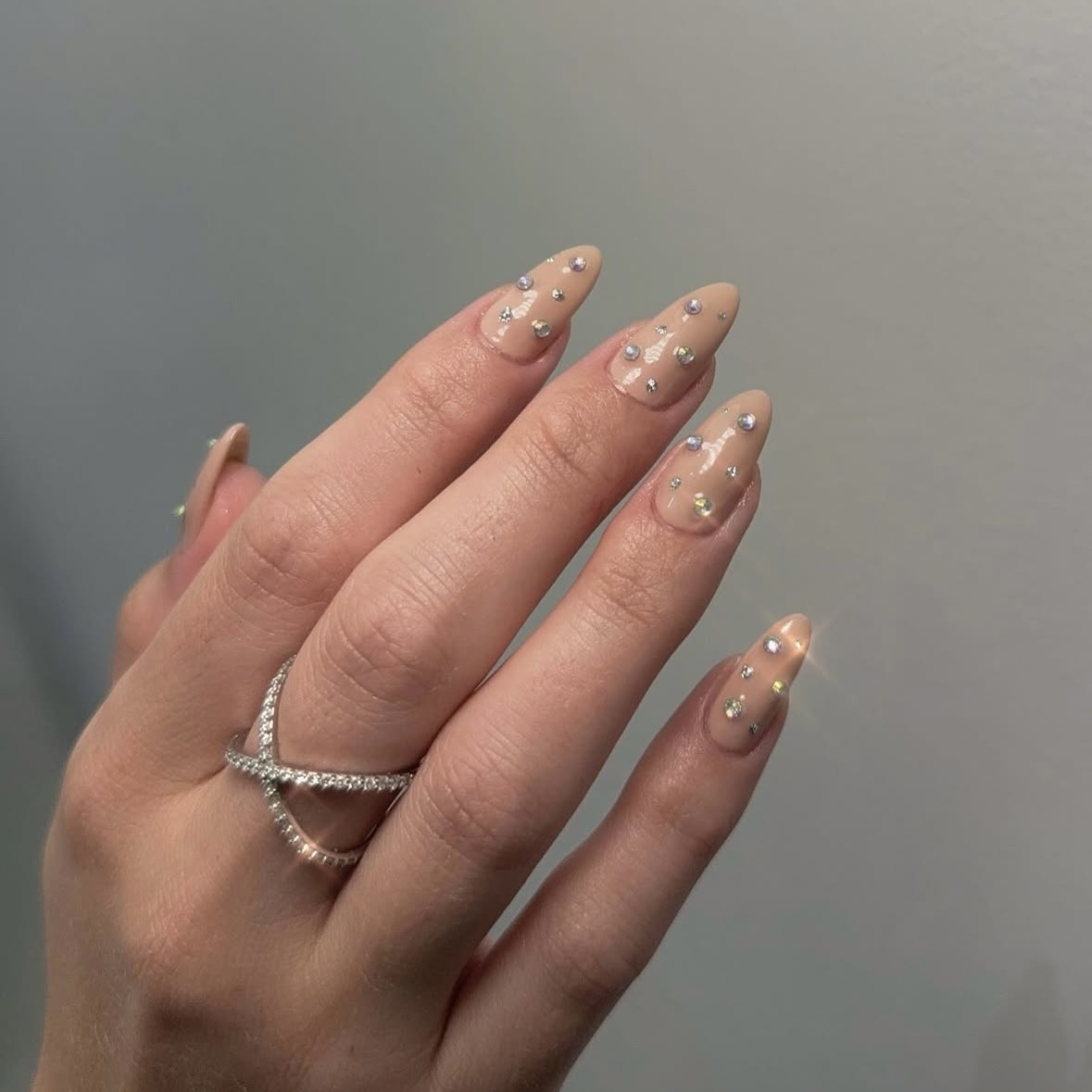 An almond-shaped French manicure with bedazzled polka dots.