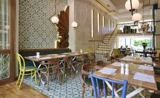 Restaurant interior with wooded and tiles floor and wooden tables with multi-coloured chairs