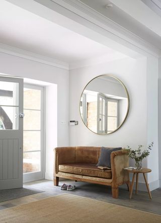 Small hallway with brown leather sofa and glass panelled front door