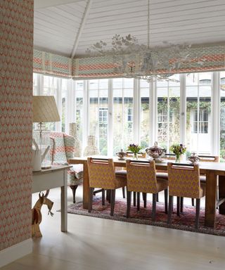 Conservatory dining room with cladding ceiling, large chandelier and pattern in Kit Kemp's house