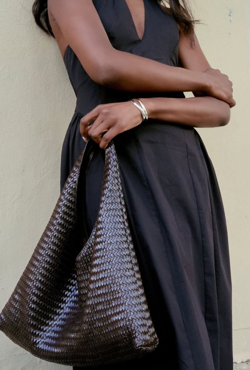 @emmanuellek_ wears a slouchy leather braided bag from Mango with a black midi halter dress and a gold bracelet