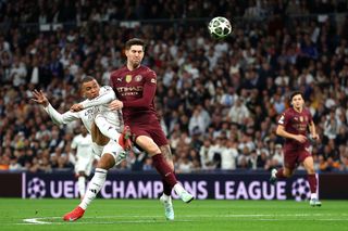 Kylian Mbappe of Real Madrid scores his team's first goal whilst under pressure from John Stones of Manchester City during the UEFA Champions League 2024/25 League Knockout Play-off second leg match between Real Madrid C.F. and Manchester City at Santiago Bernabeu Stadium on February 19, 2025 in Madrid, Spain.