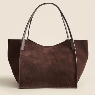 A large brown suede tote by J. Crew shot against a beige background