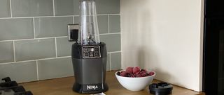 ninja blender with auto-iq bn495uk on a kitchen countertop with a bowl of berries to the right-hand side