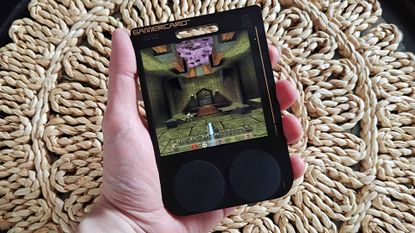 Hand holding Gamercard with Quake gameplay on screen.