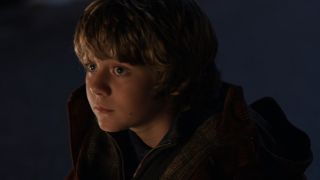 Ty Simpkins sitting outside with a sad expression in Iron Man 3.
