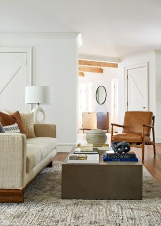 An image of a living room with a brown chair and pale sofa