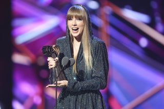 Taylor Swift onstage at the 2023 iHeartRadio music awards wearing a hooded dress