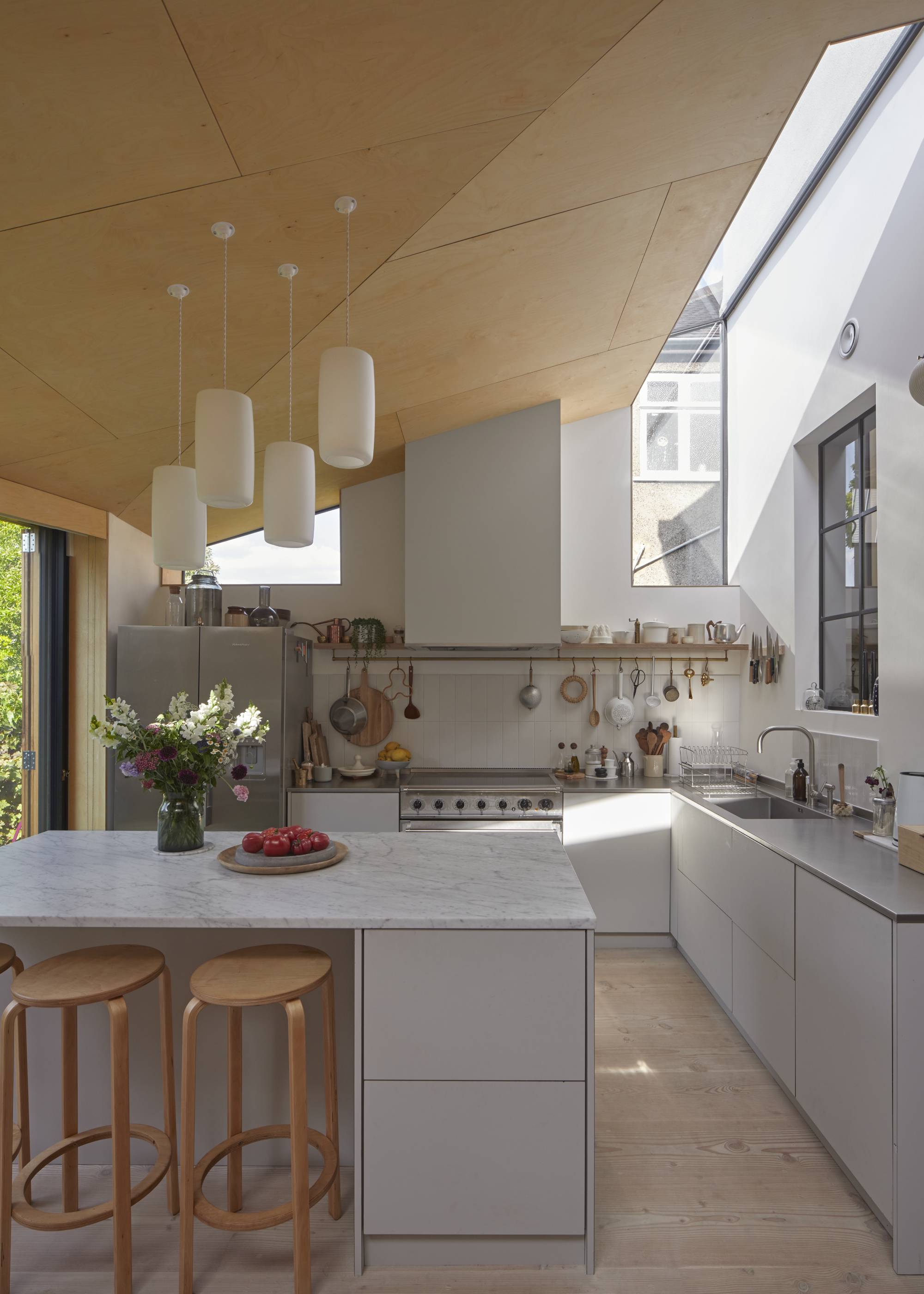 modern grey and white kitchen with plywood ceiling and rooflight