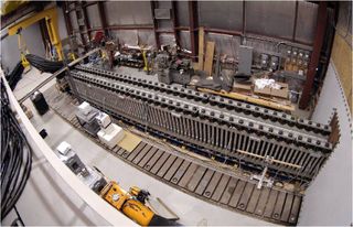 a long metal rail above a series of rectangular magnets inside a hangar