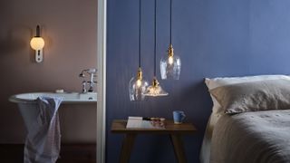 blue bedroom with low pendant lights and en suite bathroom with wall lights