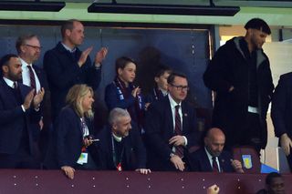 Prince George and Prince William cheering during an Aston Villa match standing among a group of people in suits and ties