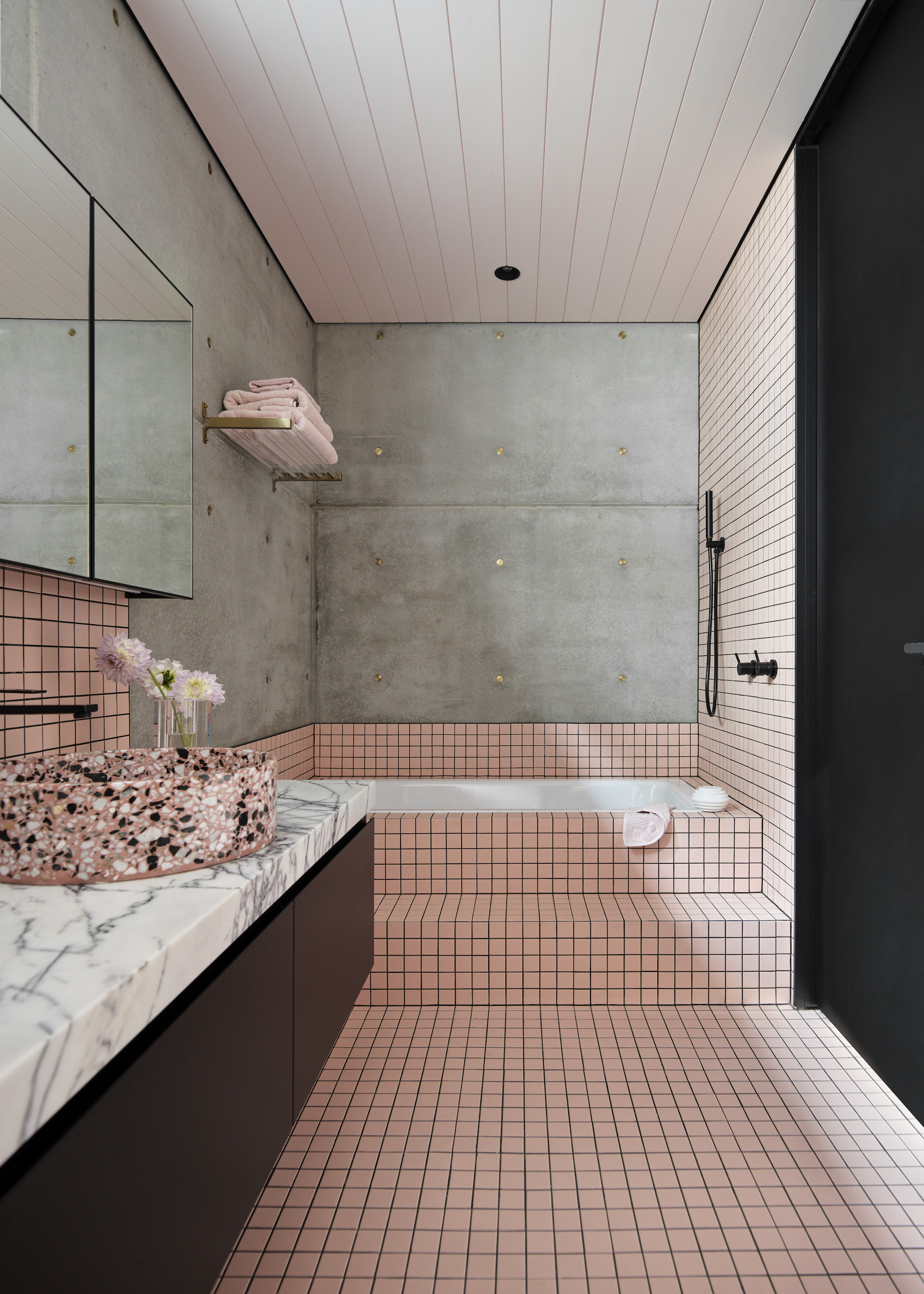 bathroom with a pink tiles bathtub and walls as well as a large vanity and sink in the corner of the space