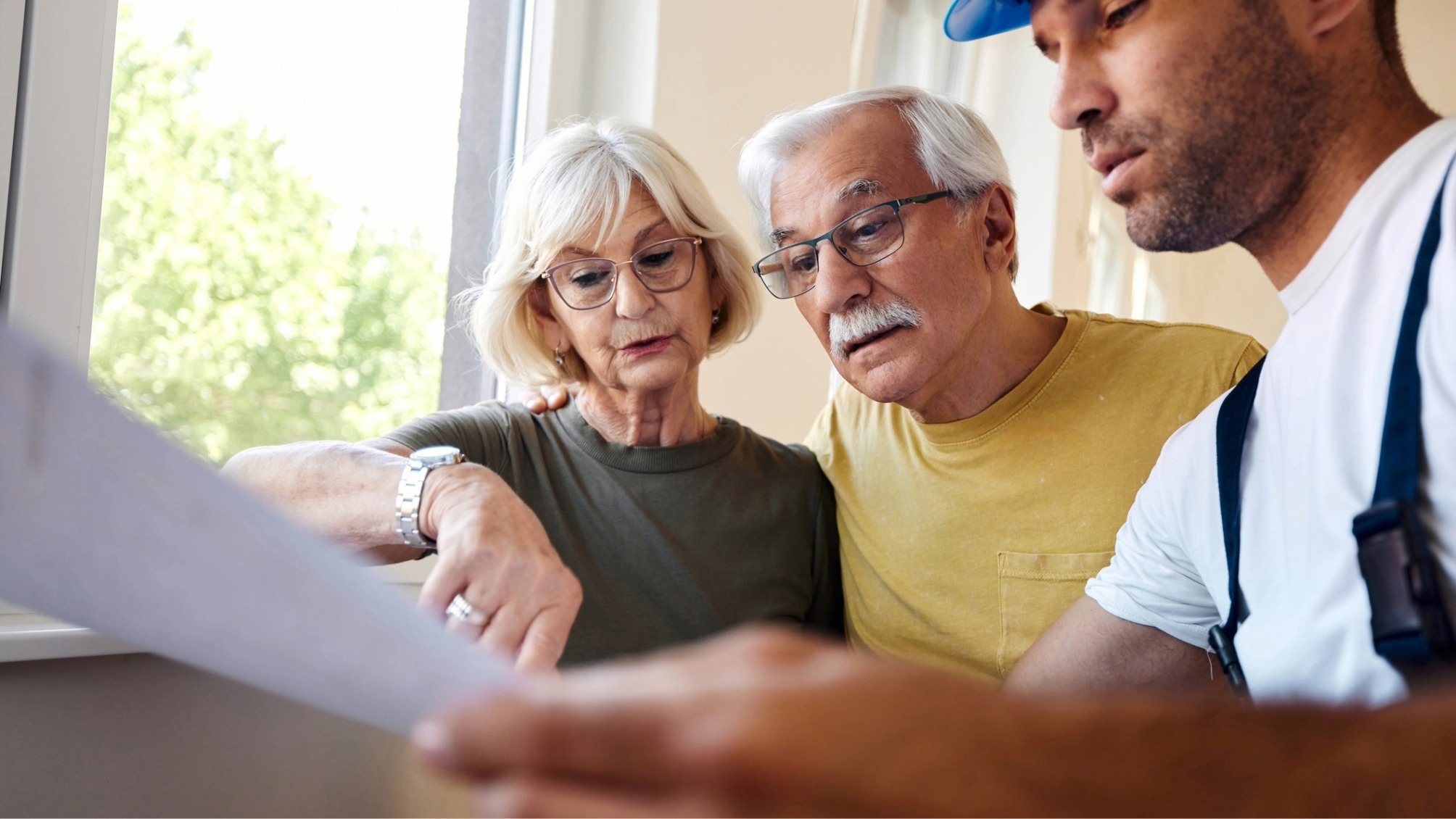 Mature couple examining blueprints with manual worker during home renovation process. 
