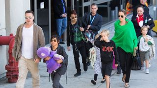 Brad Pitt, Angelina Jolie, and their children walking through an airport.