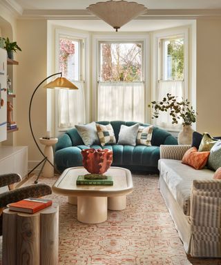 neutral victorian style living room decorated with eclectic mix of modern and vintage furniture including a curved teal sofa