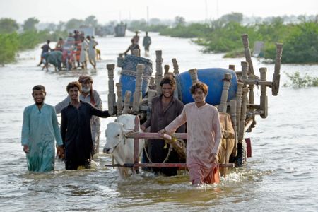 People push a cart loaded with belongings through flood water