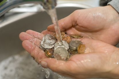 Washing coins in a sink with running water