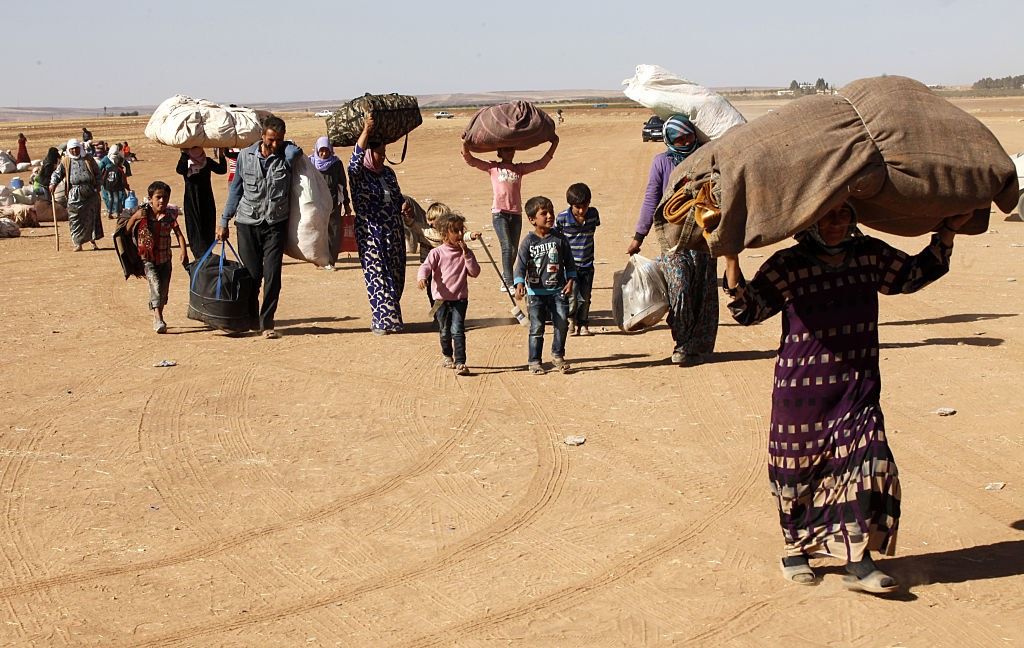 Syrian refugees walk with their belongings after crossing into Turkey on Sept. 26, 2014.