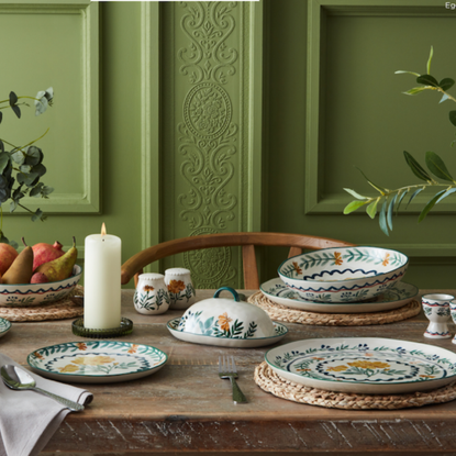 Nutmeg Wild Orchid collection on a wood dining table in front of a green period wall propery.