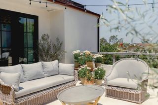 sunny balcony with grey wicker furniture and potted plants