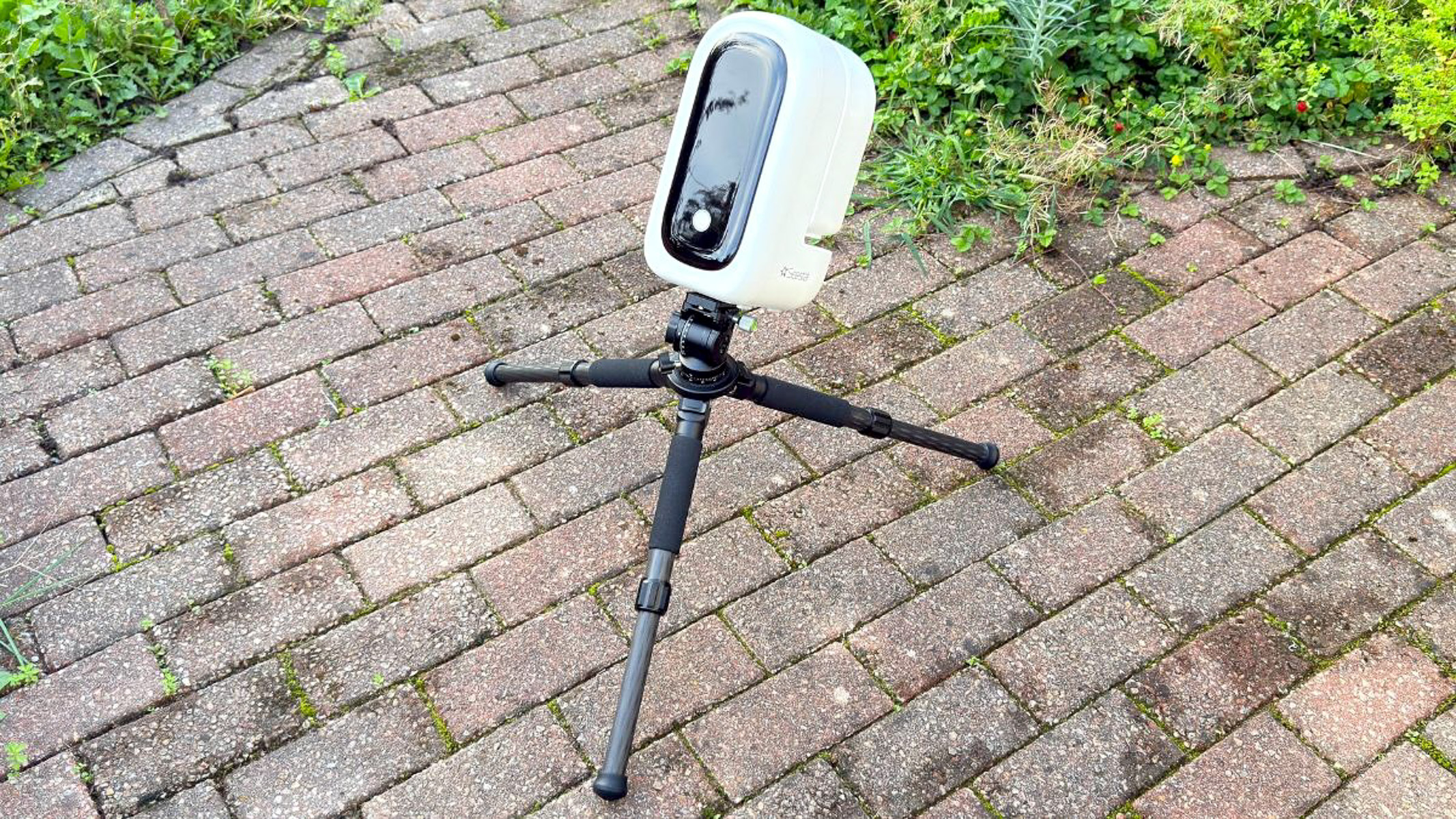 The ZWO Seestar S50 Pro in EQ mode on a tripod with a brick floor in the background.