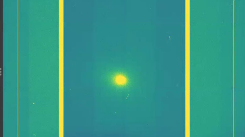A screenshot of a yellow dot which is comet 3I/ATLAS in the middle of a green and purple background