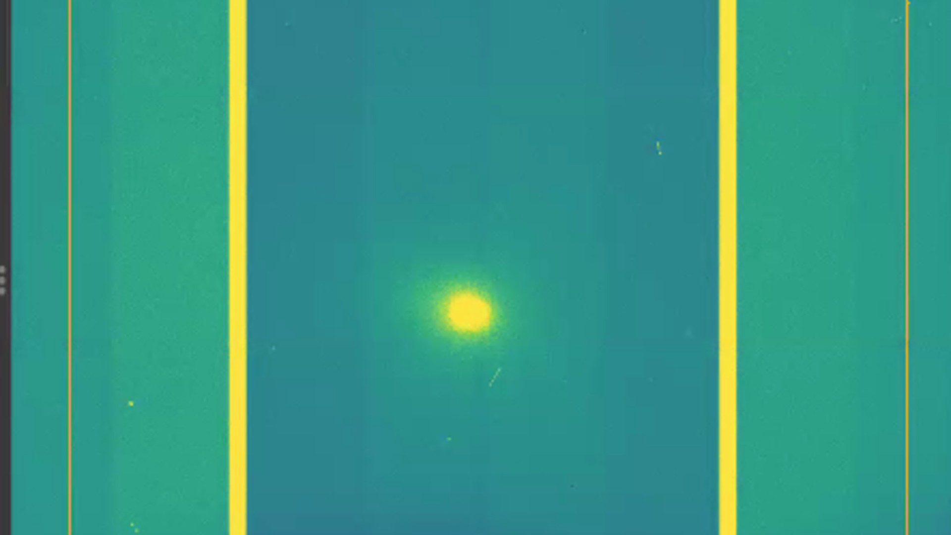 A screenshot of a yellow dot which is comet 3I/ATLAS in the middle of a green and purple background