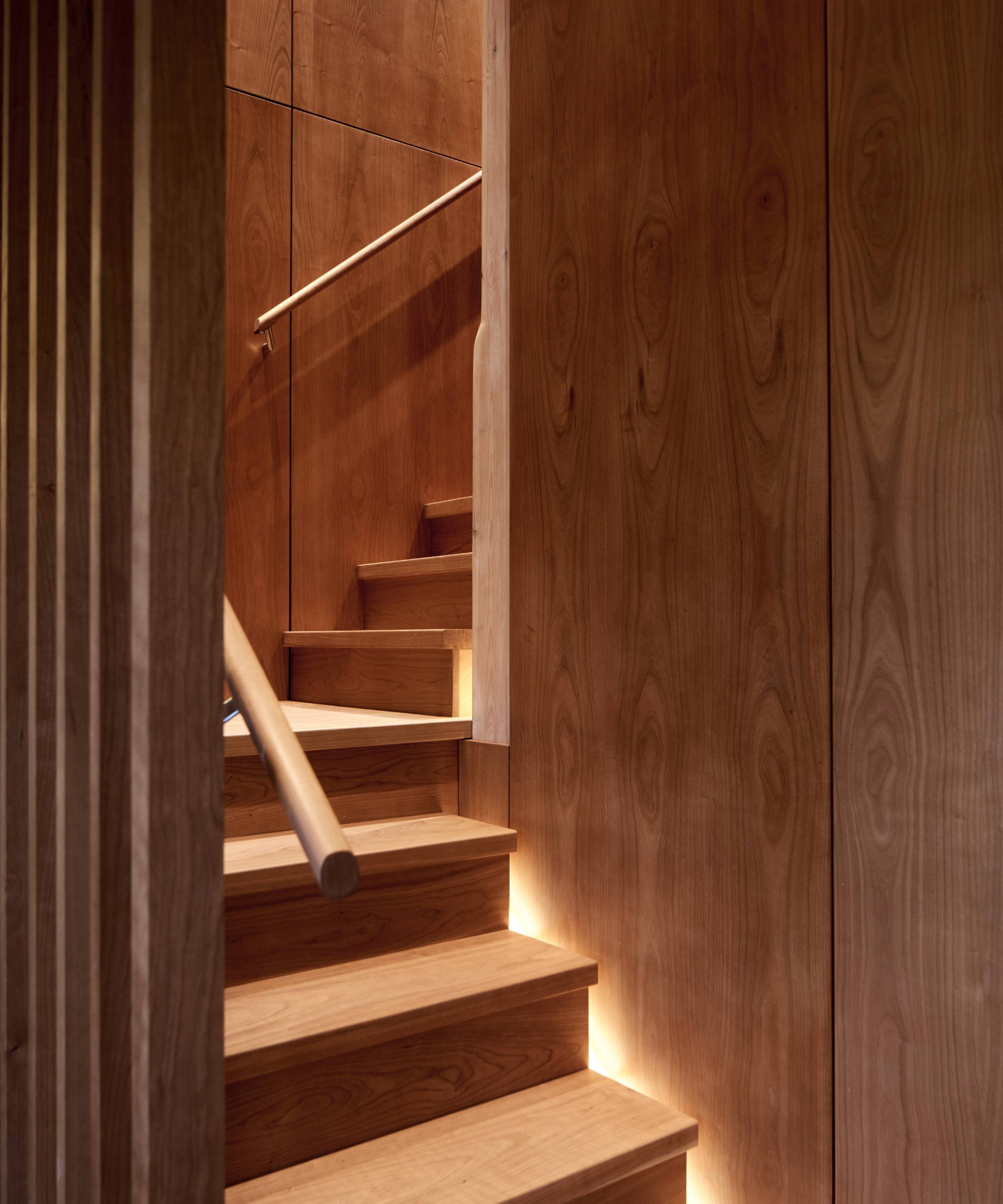 Curved wooden staircase with lights on the right hand side