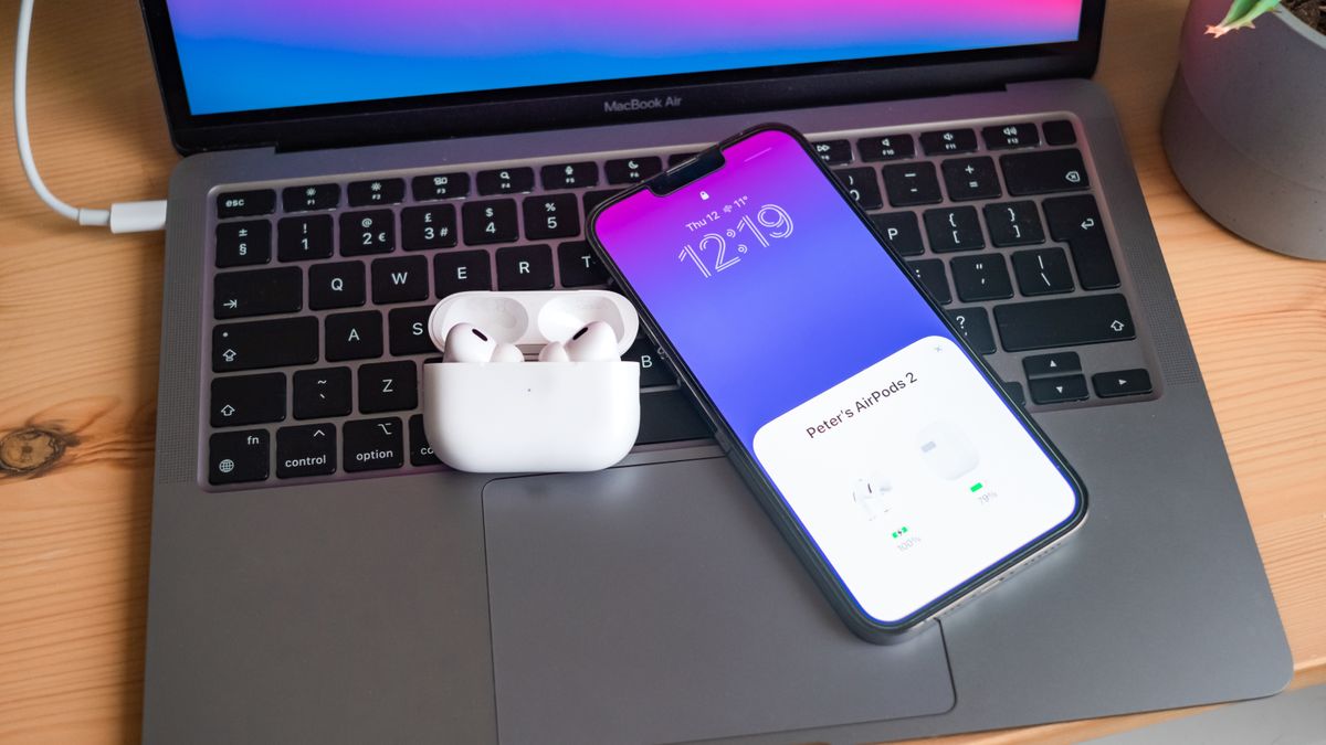 A set of AirPods Pro and an iPhone 13 Pro Max on the keyboard of a MacBook Air