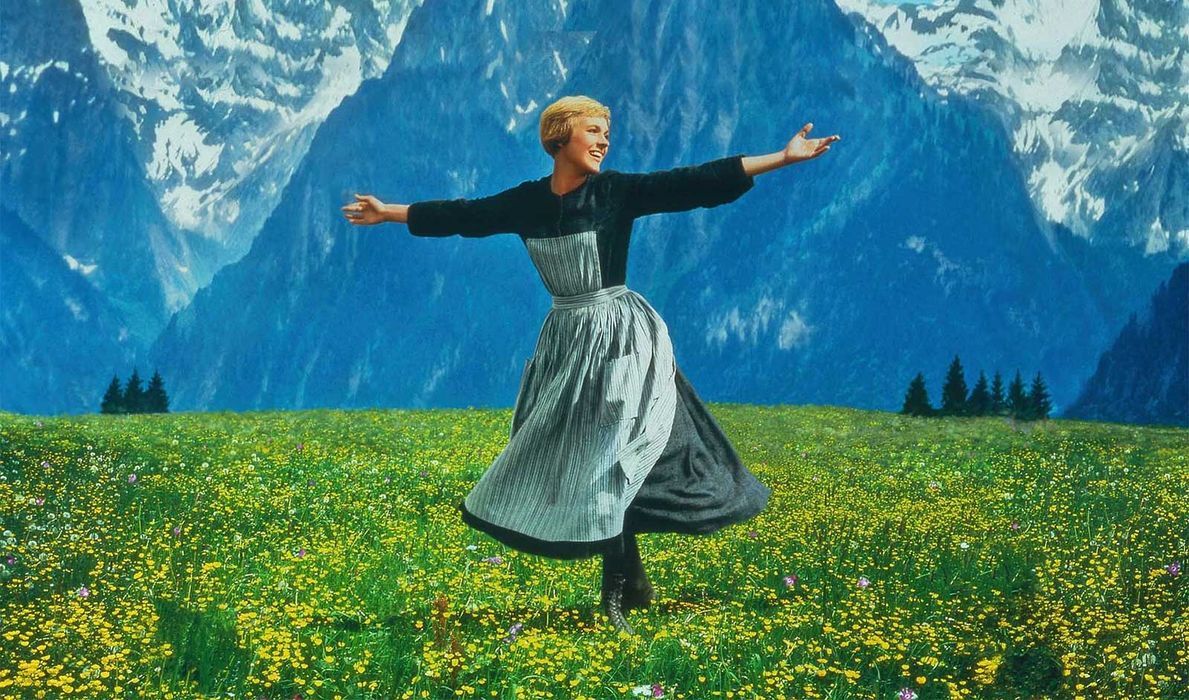 Julie Andrews as Maria smiling in a field of flowers during a scene in the Disney movie The Sound of Music.