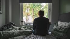 A lonely man sits by a window in a stock photo.