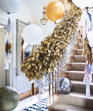 Christmas stair decor ideas with a large gold leaf garland on banister